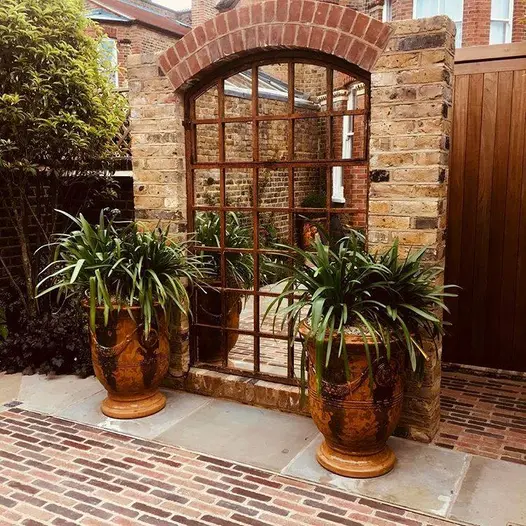 Seville mixed with Abbey Dark Multi Clay Pavers in front of urns and trompe l’oeil mirrored gate in brick wall.