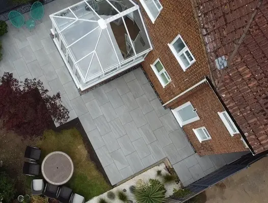 Aerial view of large patio of Kandla Grey Porcelain outdoor tiles and gravel mulched border, designed by Absolute Landscapes Ltd.