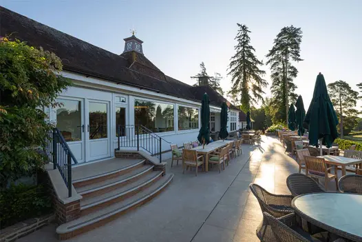 Wicker seating and wooden dining furniture on acid washed limestone paving with scenic golf course views.