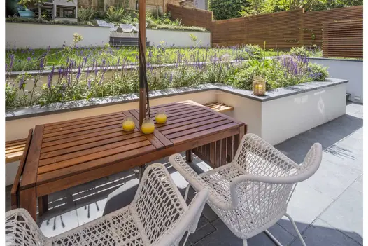 Terraced back garden with white-rendered retaining walls, grey coping and matching Brazilian Black slate paving. 