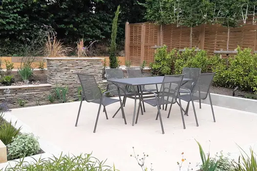 Florence Beige porcelain paving used as foundation for outdoor space adorned with metal patio furniture, offering a modern and stylish ambiance.