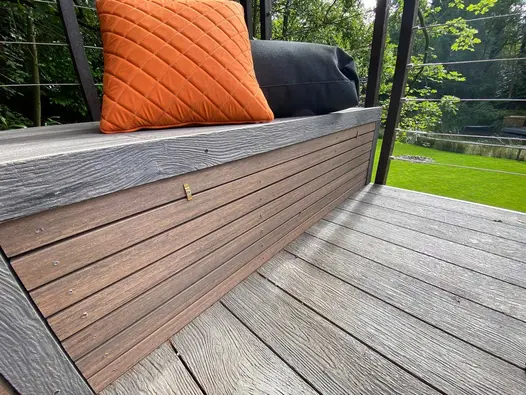 Orange cushion sits on outdoor bench using composite decking, chestnut battens create fascia on the seat.