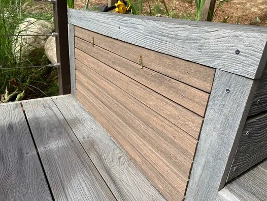 An outdoor bench come trunk using composite decking has chestnut battens creating a fascia on the seat turned storage.
