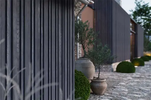 Contemporary home exterior using Anthracite Millboard Board & Batten Cladding, paired with stone paving and topiary planting.