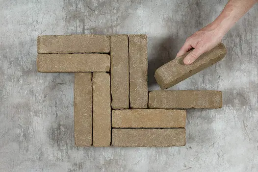 Antique Brown Clay Pavers held during laying, showing size and finish.