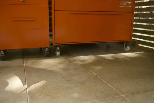Close-up of Antique Egyptian Beige Limestone paving beneath bright orange kitchen units, showing soft beige tones.