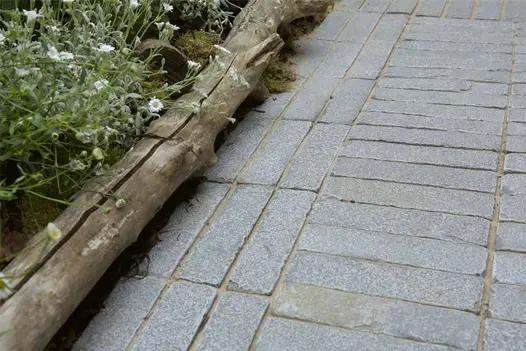 Close-up of Antique Grey Limestone pavers bordered with wildflowers and timber edging in an RHS Chelsea show garden.