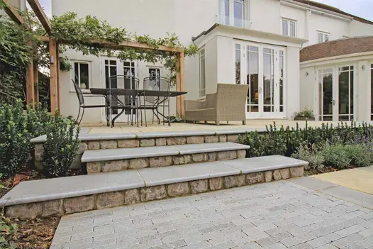 Antique Grey Limestone Steps leading to a raised dining area, paired with beige paving and matching planters.