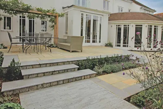 Modern garden featuring Antique Grey Limestone Steps with contrasting beige paving and lush planting.