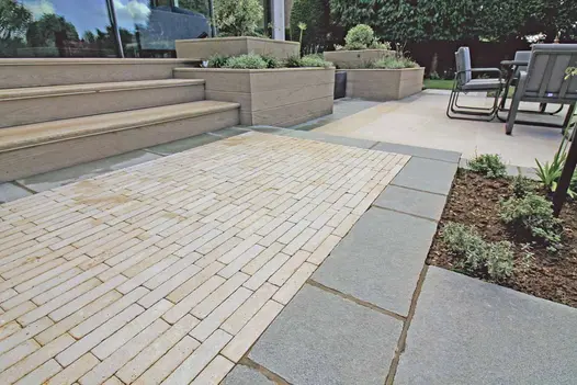 Raised planters and steps clad in Antique Grey Limestone, with Egyptian Beige Limestone pavers creating a feature pattern in a modern garden.