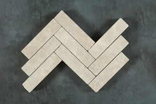 Close-up of Antique Egyptian Beige Limestone Pavers arranged in a herringbone pattern, with visible soft cream tones and rustic tumbled edges.