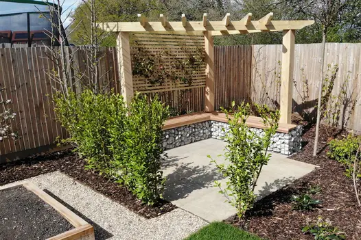 Antique Yellow limestone patio with stone-filled gabions on 2 sides forming wood-topped bench. Designed by Utopia Landscapes.