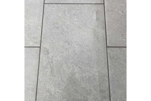 Close up of Astor Grey Porcelain Paving showing markings, with dark grey grouting and laid in running bond pattern.