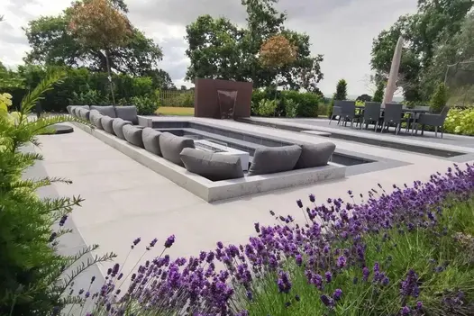 Slab Coke porcelain step treads edge sunken seating area with firepit, in middle of light grey paving. Design by Bancroft Lee.