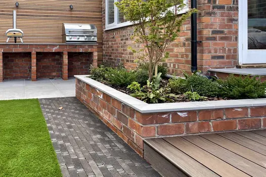 Clay paver brick path leading towards a paved and brick built barbecue with matching brick raised flower beds.