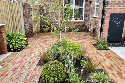 Side of house paved with mix of Westminster and Seville Clay Pavers with square-angled beds inset. Laid by Bark Brick & Block.