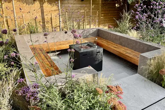 Square sunken seating area with inbuilt benches around fire pit. Boundary walls faced with Vulcano Ceniza Luxury DesignClad.