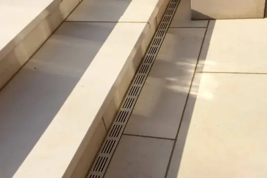 Channel drain at base of 2 steps in Beige Sawn sandstone with bullnose edge profile. Built by Hortus Landscape and Design.