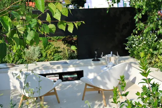 2 white chairs on Beige Smooth sandstone paving with matching coping on surrounding low wall with cubby hole for books.