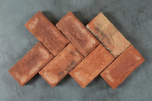 7 Romsey Antique Belgian bricks laid as small section of herringbone pattern against grey background. Free UK delivery available.