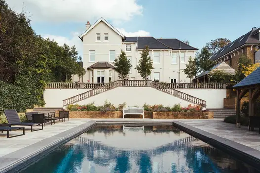 2 flights of steps descend from terrace to swimming pool edged with Black Granite coping stones. Design by Langdale Landscapes.
