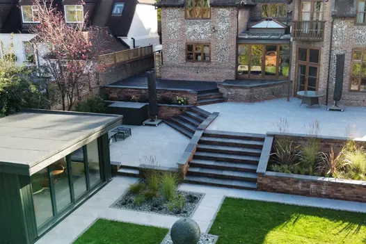 Back garden on 4 levels, with Black Slate Bullnose steps between each patio area descending to rectilinear lawn and beds at bottom.