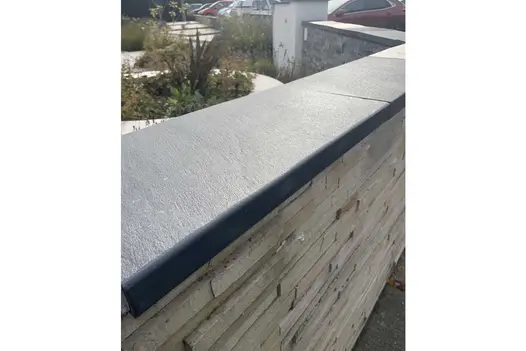 View along top of stone-clad wall capped with Brazilian Black slate coping with 5mm pencil round profile.