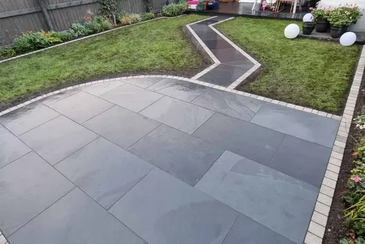 Modern garden transformation featuring Brazilian Black Slate paving bordered with light coloured paving setts.