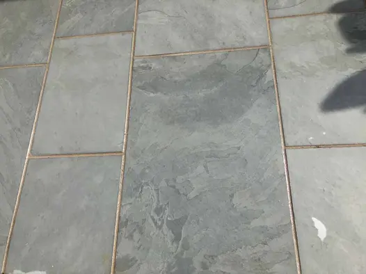 Close-up of Brazilian Grey slate paving slabs of different widths, laid with narrow joints, showing stone markings.