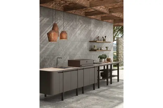 Grey outdoor kitchen units on Brera porcelain paving, sheltered by overhead canopy.
