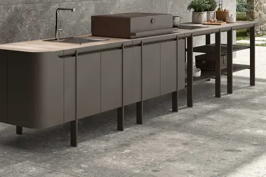 Grey kitchen units with sink  sits on Brera 800x800 porcelain paving, with matching wall behind. 
