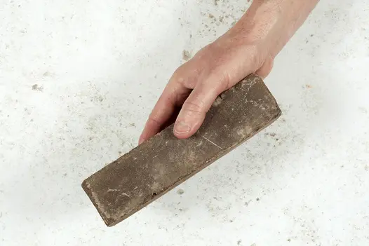 Hand holds one verona dutch clay paver against light background showing size, colour and texture. Free UK delivery.