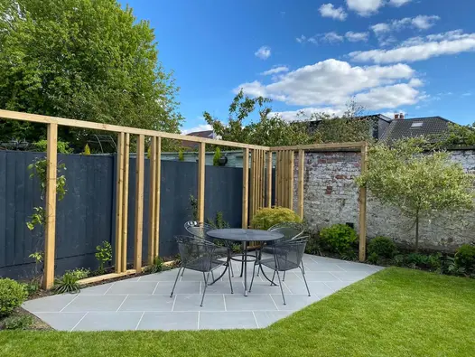 Outdoor table and chairs on rectangular patio of Trendy Black Porcelain Outdoor Tiles laid at 45° angle in corner of garden.