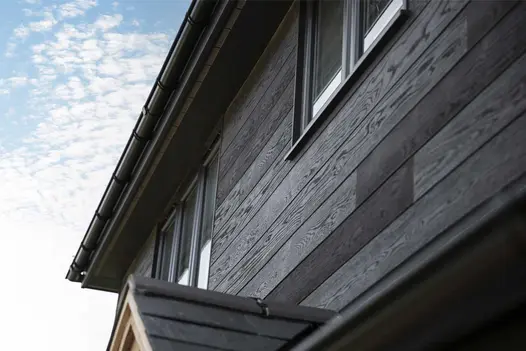 Modern home exterior clad in Burnt Cedar Millboard Shadow Line cladding, with realistic dark timber appearance and grain detail.