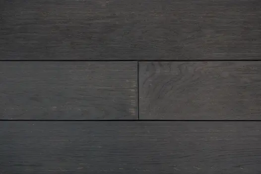Close-up of a few planks of Burnt Cedar Millboard composite decking, showing tones and brushed texture.