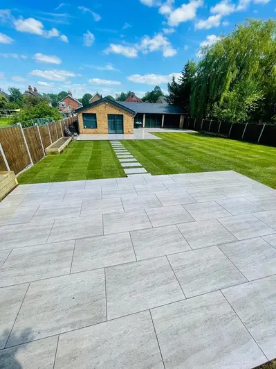 Looking from a porcelain patio with contrasting dark grout towards a bungalow on a sunny day.