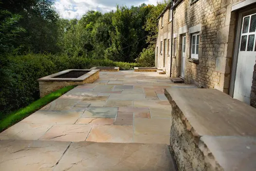 Step down to rear of rural stone-built cottage with Camel Dust sandstone patio running along length of building. 