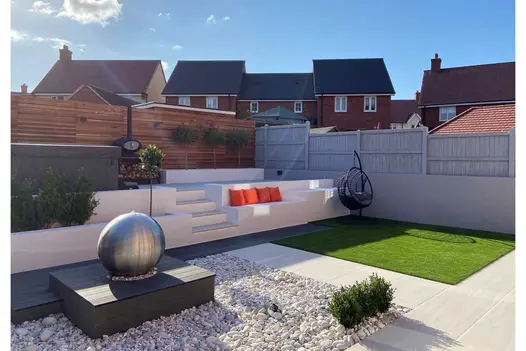 Terraced area in Faro porcelain paving with steps down to Charcoal DesignBoard composite decking on edge of water feature and lawn.
