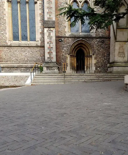 View of St. Albans Cathedral shows charcoal grey brick pavers running up to the front steps. By J & L Gibbons.
