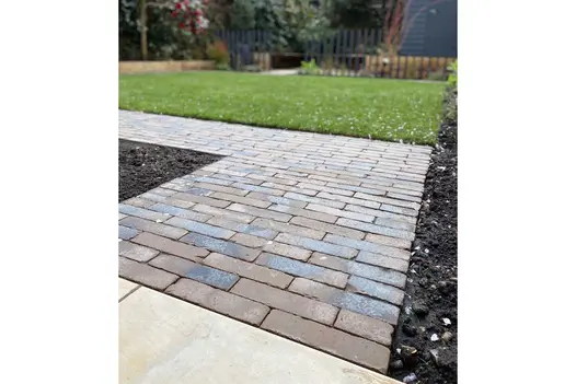 Path Chelmer Valley Aldridge Clay Paving turns corner between borders, lawn and sandstone paving. Design by Robert Jackson Gardens.