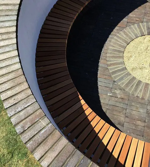 Curved sunken seating with unbound Chelsea clay pavers laid stackbond around mortared pavers cut to fit edge of circle of gravel.