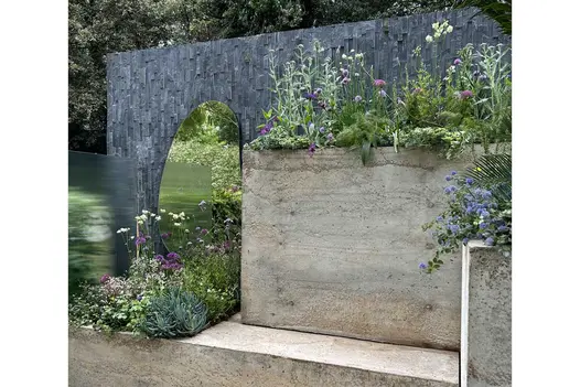 Wall with Black Slate cladding applied vertically, behind large oval mirror and tall tufa bed. Design by Chelsea Gardener.