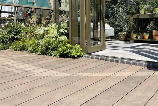 Greenhouse with doors open onto Chestnut Brushed DesignBoard edged by foliage. Design by Llevelo. Built by Stewart Landscape.