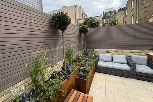 composite battens surround garden using slab khaki porcelain paving on patio with steel corten planter display.