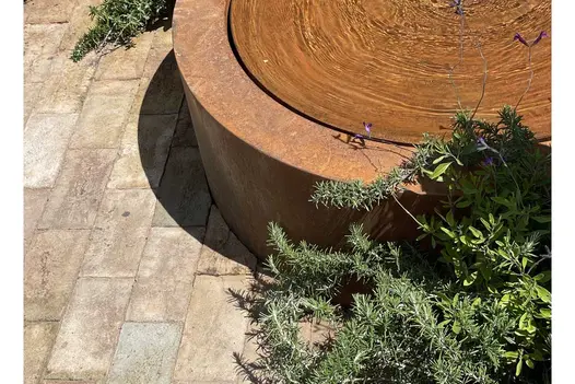 Corten steel water feature with Mediterranean herbs planted next to London Mixture clay pavers in RHS Hampton Court show garden.