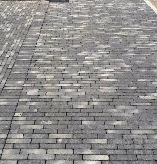 Wide area paved with Silver Grey Multi clay pavers laid running bond in 2 directions, with soldier course separating them.