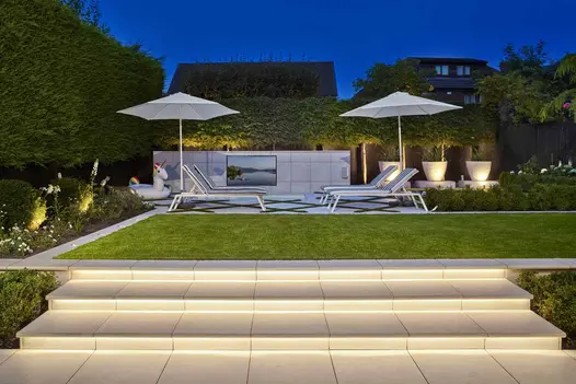 Comblanchien porcelain garden steps with led strip lights leading to swimming pool relaxation area paved light porcelain tiles.