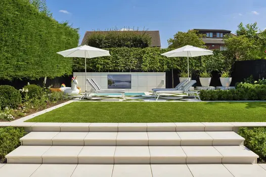 Contemporary scheme with wide porcelain steps leading to grass area overlooking Comblanchien porcelain patio with swimming pool.