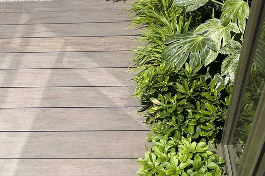 Contrasting shrubs fill border next to Chestnut Brushed DesignBoard WPC decking. Hartley Botanic trade stand designed by Llevelo.