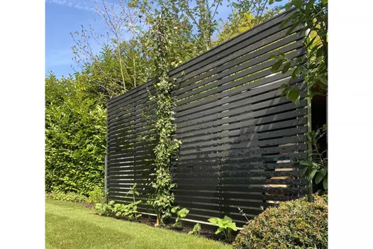 Dark Ash composite screening battens used as tall screen at edge of lawn with low planting. Designed by Thouvenin Landscapes.